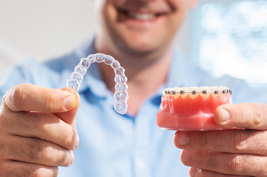 chico mostrando una ortodoncia invisible y una dentadura con brackets