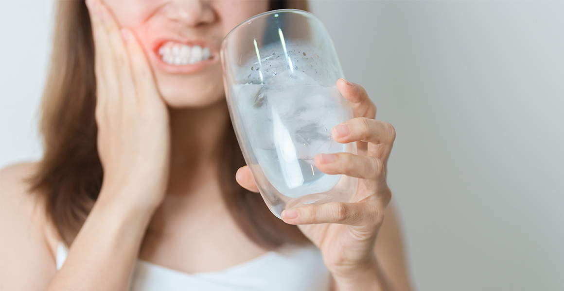 mujer que sufre sensibilidad dental al beber agua